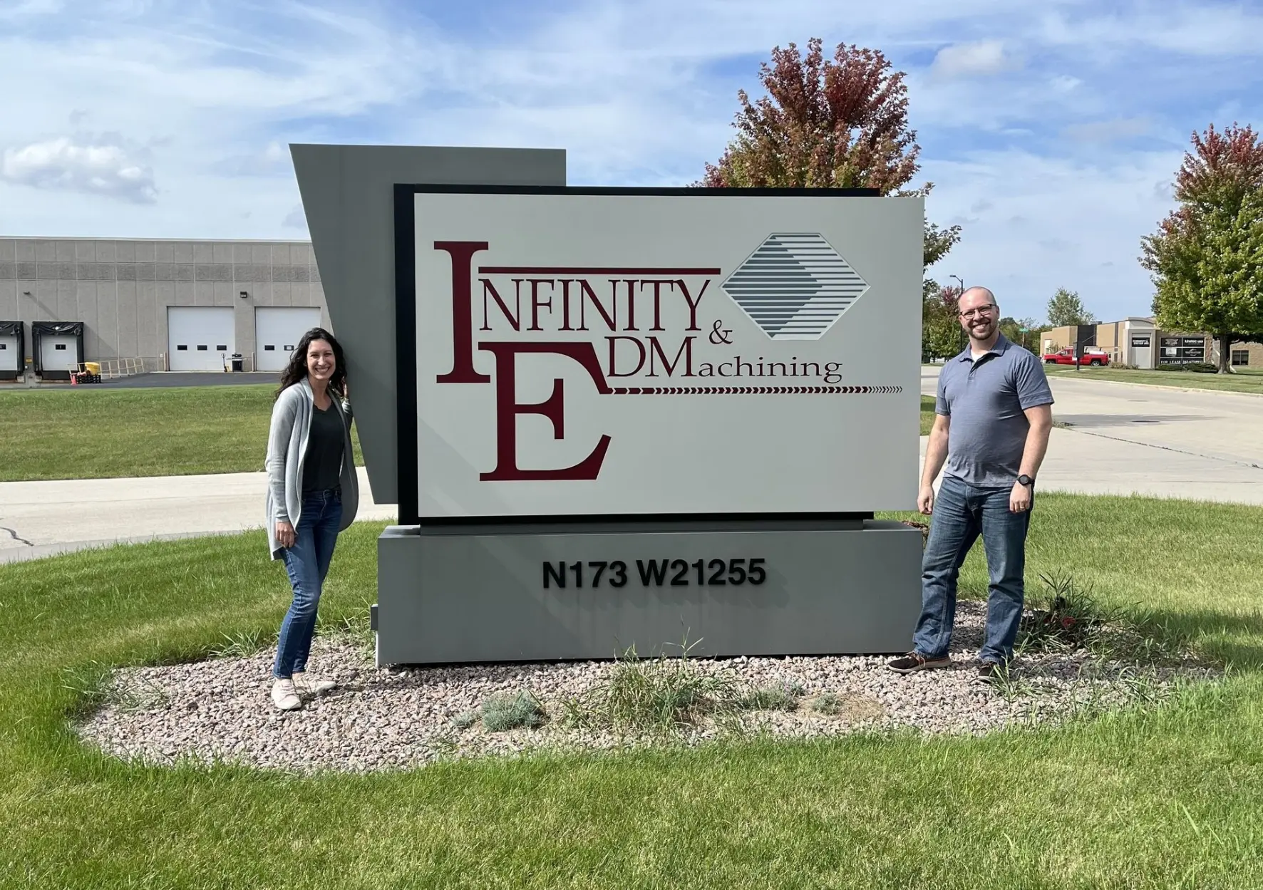 New owners in front of Infinity EDM and Machining sign