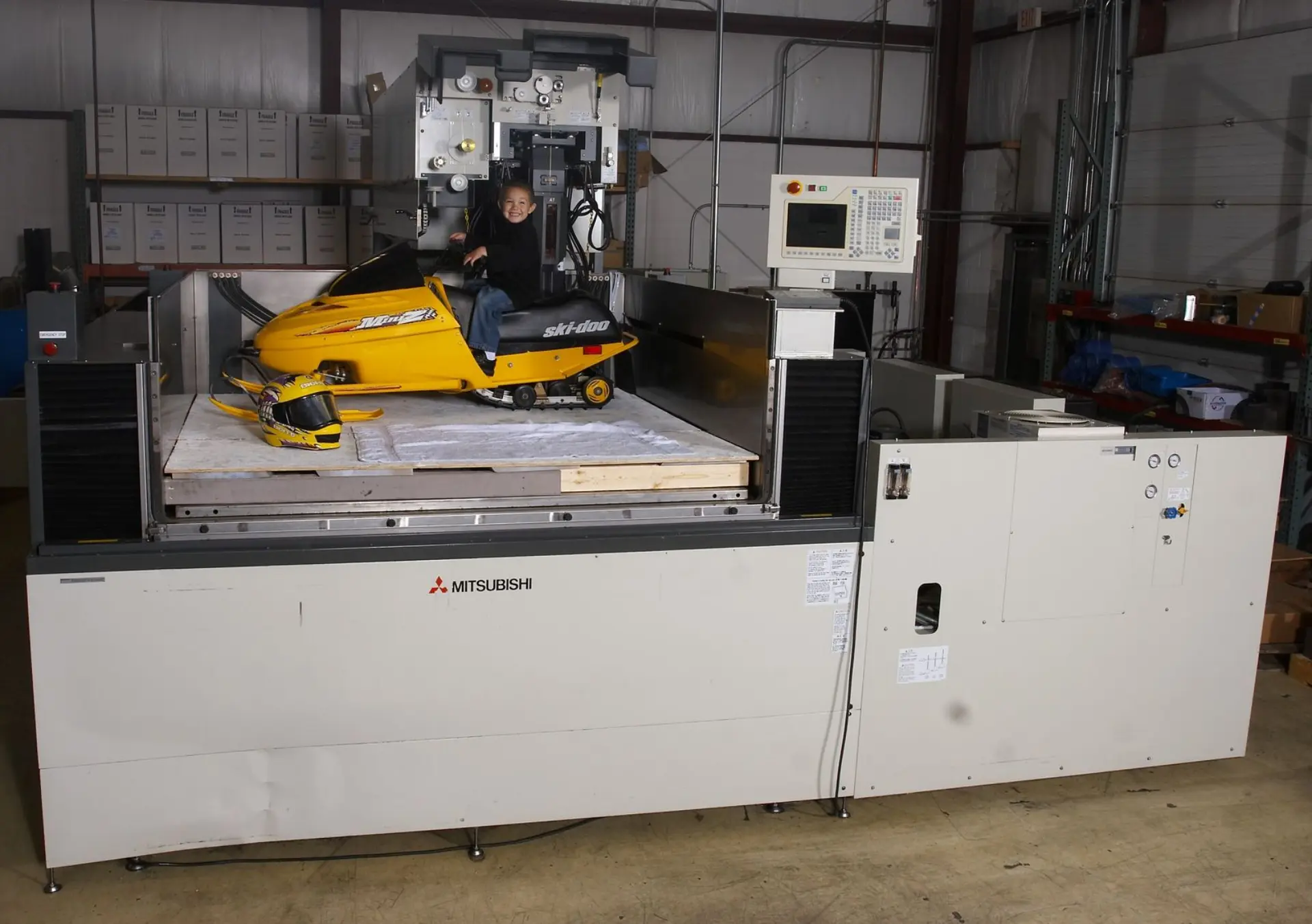 Little Boy on Mini Snowmobile in the bed of a FA50 Wire EDM Machine